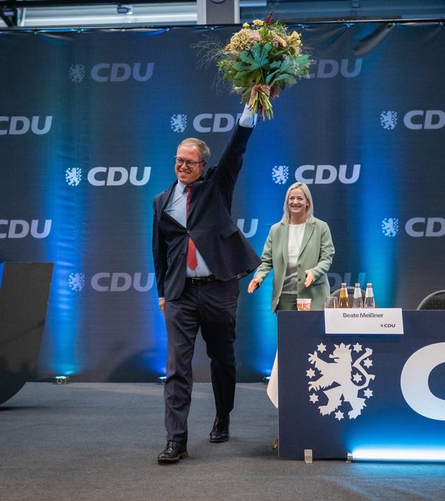 Mario Voigt (CDU, l), Ministerpräsident von Thüringen, winkt nach seiner Wiederwahl zum Landesvorsitzenden der CDU Thüringen mit einem Blumenstrauß