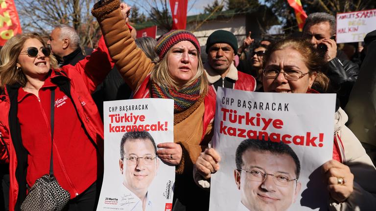 09.03.2026, Türkei, Istanbul: Unterstützer rufen Slogans vor dem Silivri-Gefängnis, in dem der inhaftierte Bürgermeister von Istanbul, Ekrem Imamoglu vor Gericht steh. Auf den Plakaten ist auf Türkisch zu lesen: "Türkiye wird gewinnen".