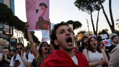 Ein Demonstrant hält ein Schild mit Flamingo hoch