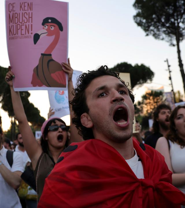 Ein Demonstrant hält ein Schild mit Flamingo hoch
