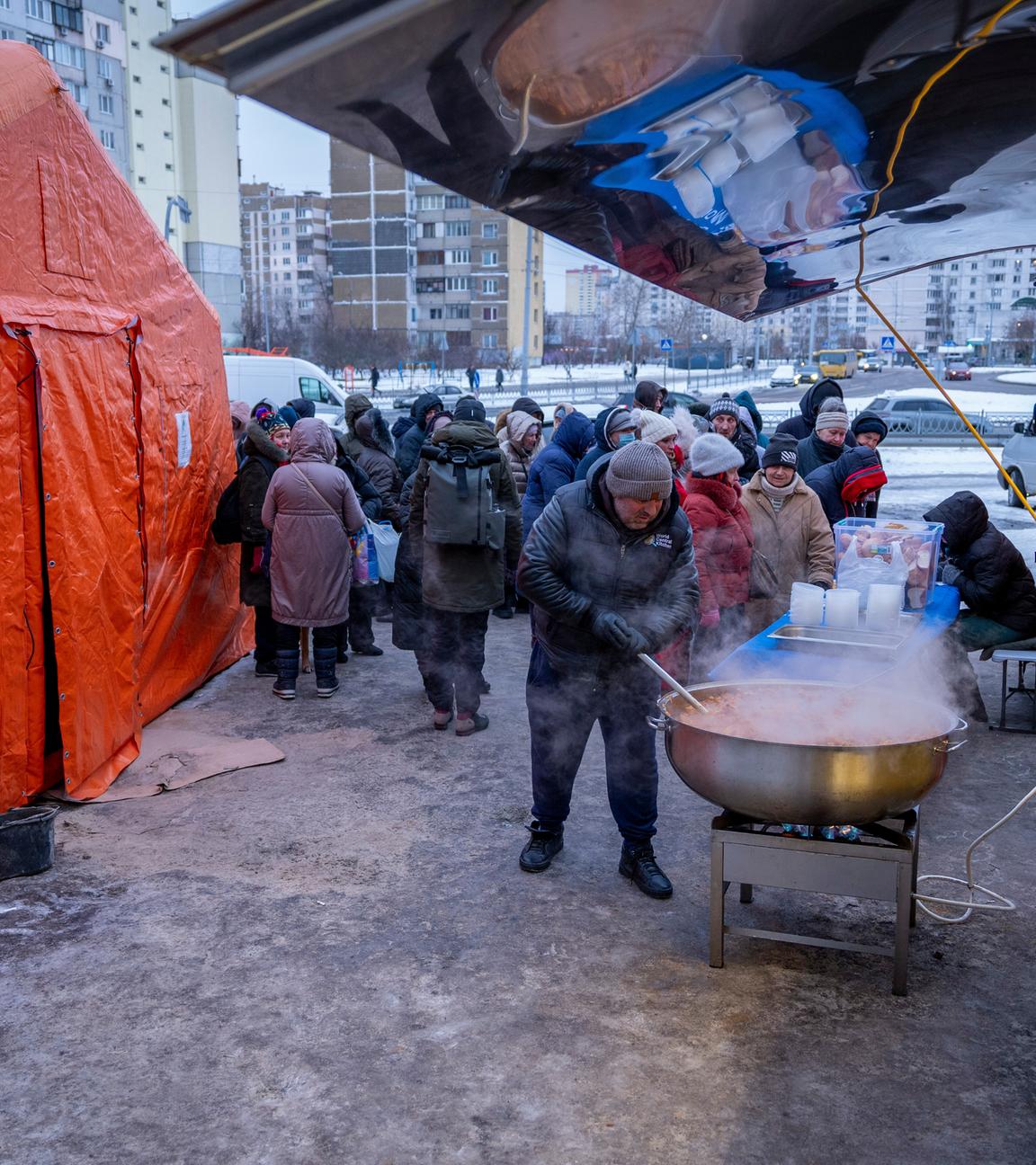 30.01.2026, Ukraine, Kiew: Menschen, die nach den russischen Luftangriffen ohne Strom sind, warten in einem Wohnviertel auf kostenlose warme Mahlzeiten.