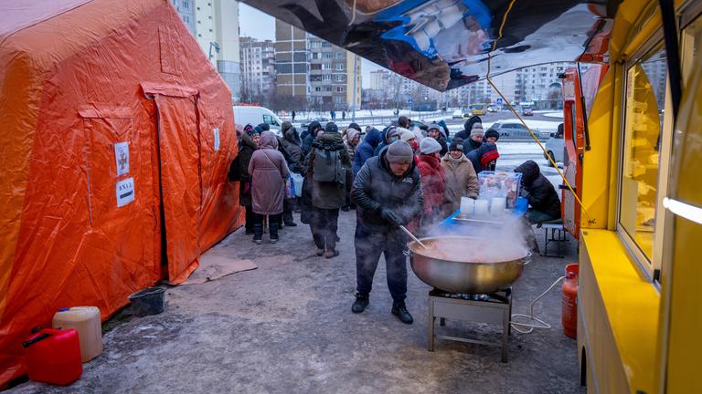 30.01.2026, Ukraine, Kiew: Menschen, die nach den russischen Luftangriffen ohne Strom sind, warten in einem Wohnviertel auf kostenlose warme Mahlzeiten.