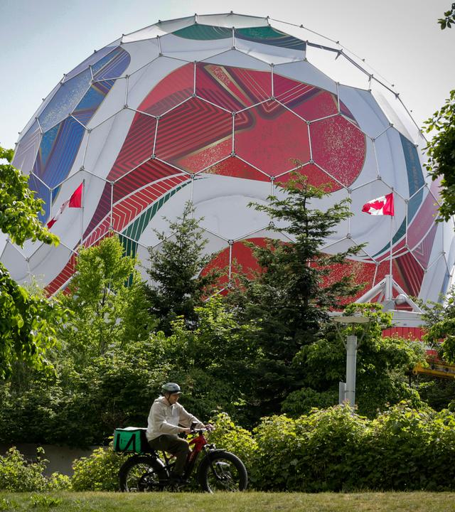 Ein Mann fährt an der Kuppel von «Science World» vorbei, die im Vorfeld des Turniers in einen riesigen offiziellen Spielball der FIFA Fußball-Weltmeisterschaft 2026 verwandelt ist.