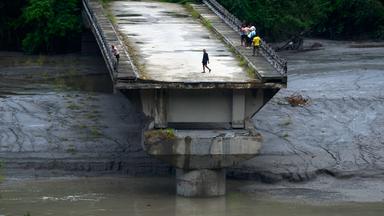 30.08.2026, Nepal, Dhading: Menschen stehen auf den Überresten einer Brücke, die über den Fluss Trishuli führte und bei Sturzfluten weggespült wurde.