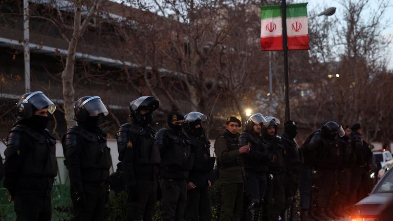 Iranische Bereitschaftspolizei steht Wache, während Studenten vor der britischen Botschaft in Teheran, Iran, am 14. Januar 2026 protestieren. Der Iran erlebt seit dem 8. Januar 2026 einen landesweiten Internetausfall, während sich die Welle der regierungsfeindlichen Proteste verstärkt.