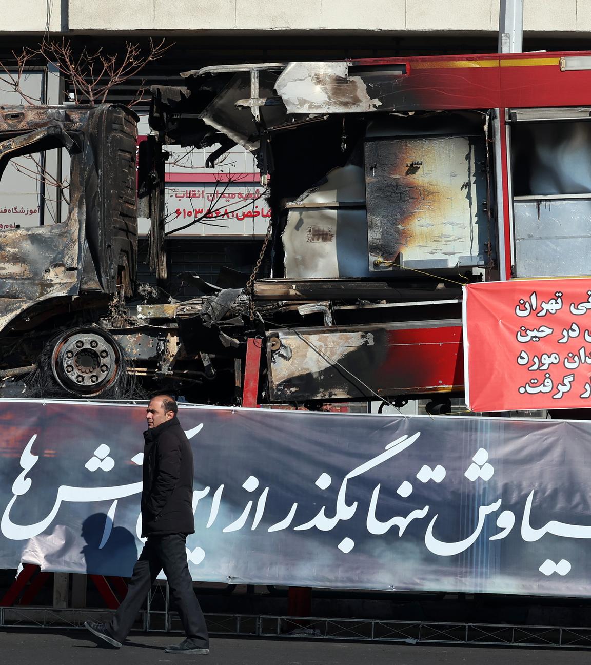 Ein Mann geht neben den Trümmern eines Feuerwehrfahrzeugs vorbei, das während der Anti-Regierungs-Proteste in einer Straße in Teheran in Flammen aufgegangen ist.
