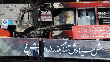 Ein Mann geht neben den Trümmern eines Feuerwehrfahrzeugs vorbei, das während der Anti-Regierungs-Proteste in einer Straße in Teheran in Flammen aufgegangen ist.