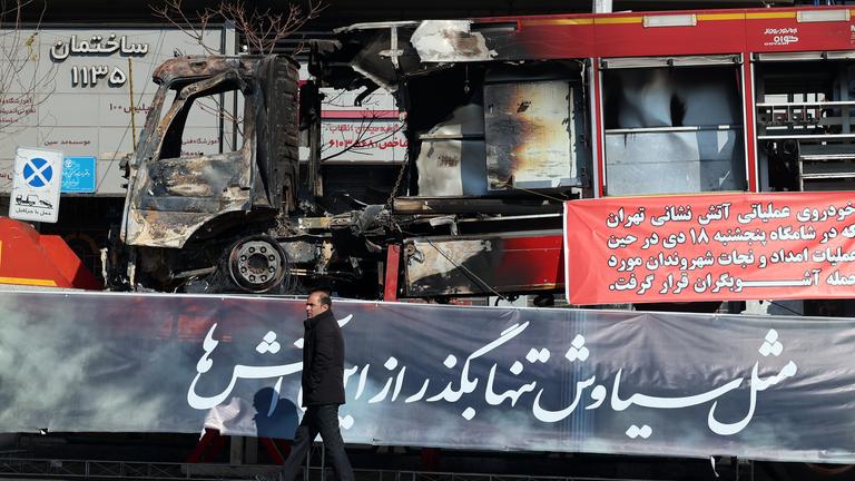 Ein Mann geht neben den Trümmern eines Feuerwehrfahrzeugs vorbei, das während der Anti-Regierungs-Proteste in einer Straße in Teheran in Flammen aufgegangen ist.
