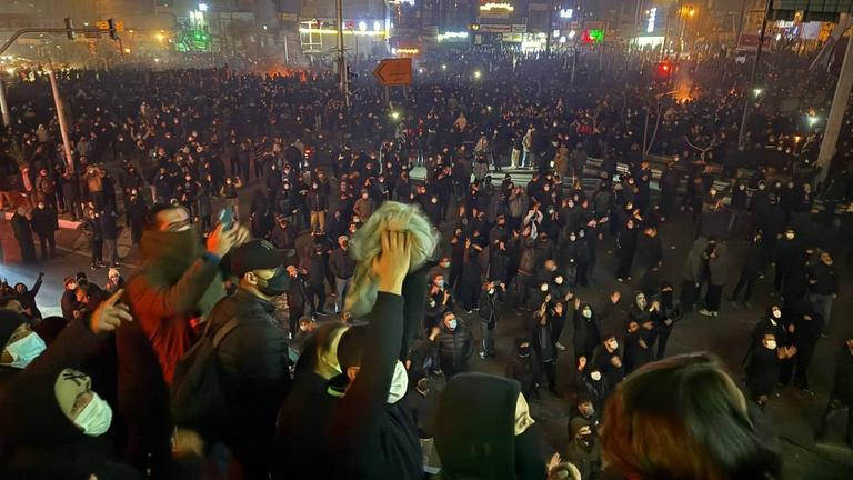 Protestierende gegen die iranische Regierung versammeln sich bei Nacht auf einem Platz.