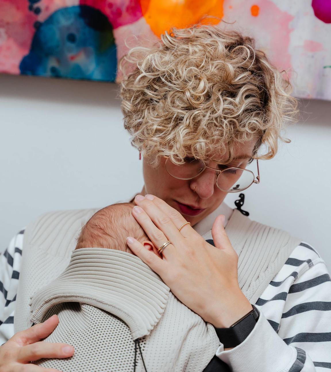 "37°Leben: Das Wochenbett - Glückshormone und Albträume": Jacqui trägt ihren Sohn Sohn Jonah im Tragetuch vor sich und schaut ihn an.