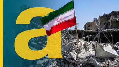 Die iranische Flagge steht auf den Trümmern eines zerstörten Gebäudes.