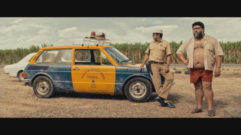 2 Männer stehen vor einem Polizeiauto in dem Film "The Secret Agent"