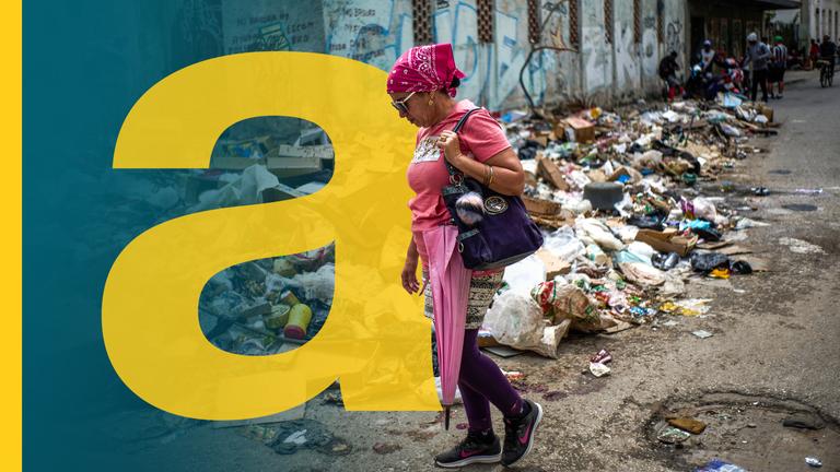 Eine Frau läuft vor einem Müllhaufen auf der Straße entlang.