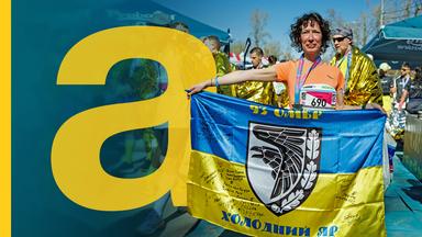 Eine Frau hält eine ukrainische Fahne in Händen, nachdem sie an einem Marathon teilgenommen hat.