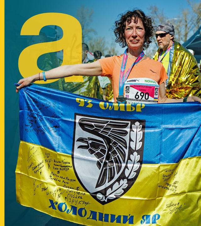 Eine Frau hält eine ukrainische Fahne in Händen, nachdem sie an einem Marathon teilgenommen hat.