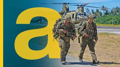 Zwei US-Soldaten vor Militärhubschraubern auf einem US-Stützpunkt.