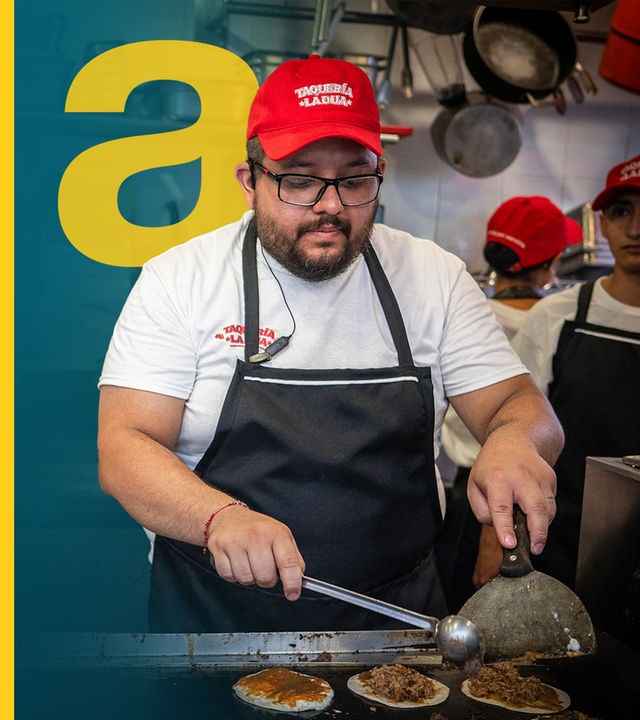 Ein Mitarbeiter eines Taco-Foodtrucks in Mexiko bereitet auf einem Straßenmarkt Essen zu