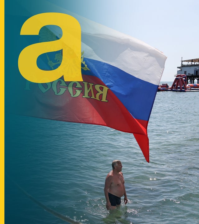 Mann badet im Schwarzen Meer in Sotschi, neben ihm eine Russland-Fahne.