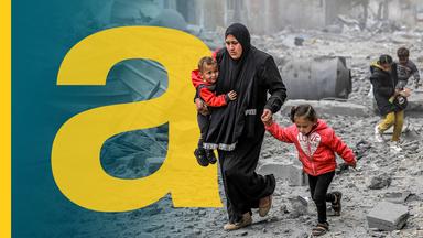 Eine Mutter läuft mit ihren beiden Kindern vorbei an zerstörten Häusern in Gaza.