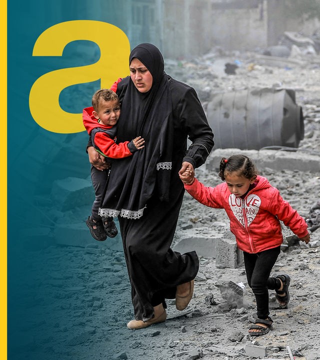Eine Mutter läuft mit ihren beiden Kindern vorbei an zerstörten Häusern in Gaza.