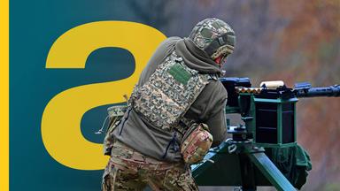 Ein Soldat von hinten, der an einer Schießanlage/Gewehr steht.