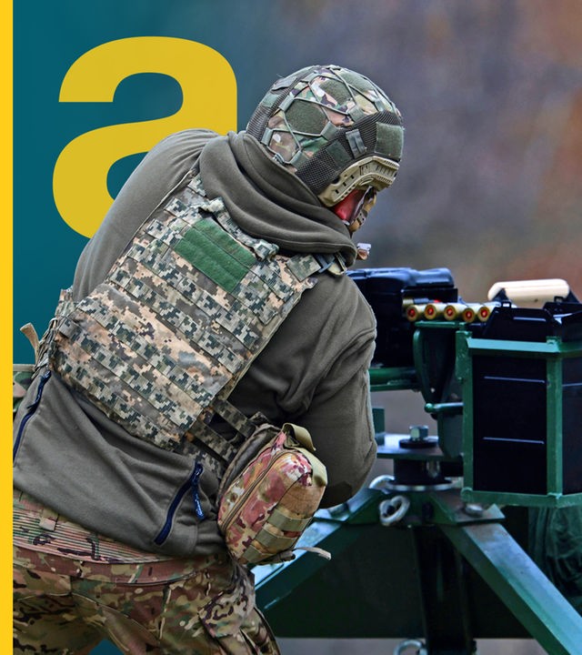 Ein Soldat von hinten, der an einer Schießanlage/Gewehr steht.