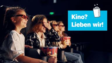 Kinder sitzen im dunklen Kino mit Popcorn – ein Mädchen hält sich dabei die Augen zu. "Kino? Lieben wir!" 