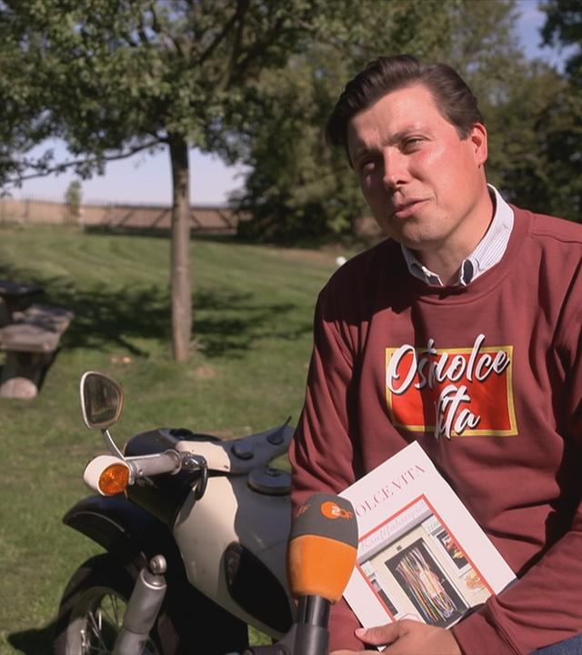 "Ostfluencer" und Pfarrer Justus Geilhufe lehnt an einem Motorrad und wird interviewt