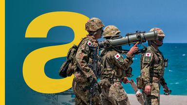 Drei japanische Soldaten bei einer Übung auf den Philippinen vor dem blauen Meer.