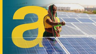 Eine Frau sprüht mit einem Schlauch Wasser auf ein Photosolar-Panel