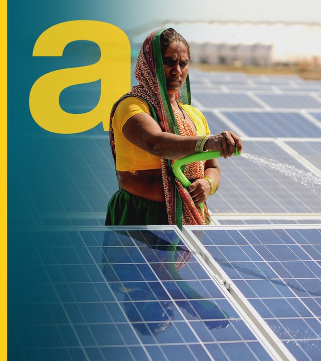 Eine Frau sprüht mit einem Schlauch Wasser auf ein Photosolar-Panel