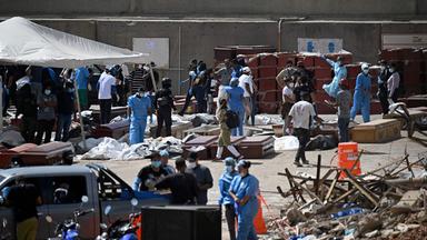 Graphic content / Forensic experts carry out body identification work on corpses laid out on the ground near coffins at a makeshift morgue in the port of La Guaira, La Guaira State, Venezuela on June 29, 2026, following the June 24 twin earthquakes. Hopes were fading on June 29, 2026 of finding survivors more than four days after powerful twin earthquakes struck Venezuela, as residents grow increasingly frustrated with the government's response to the disaster that has killed at least 1,450 people and left tens of thousands unaccounted for.