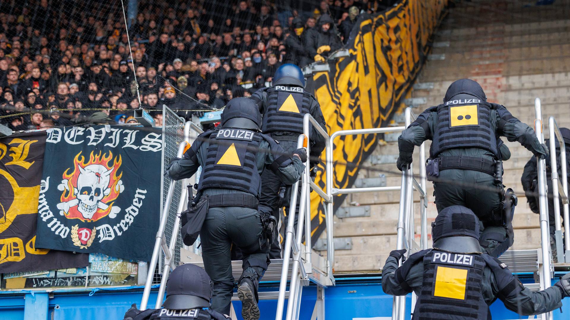 Polizisten steigen hoch auf den Gästeblock beim Spiel Hansa Rostock und Dynamo Dresden