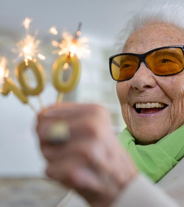 Friedel Zimmermann hält brennende Wunderkerzen in Form einer 100 in der Hand.