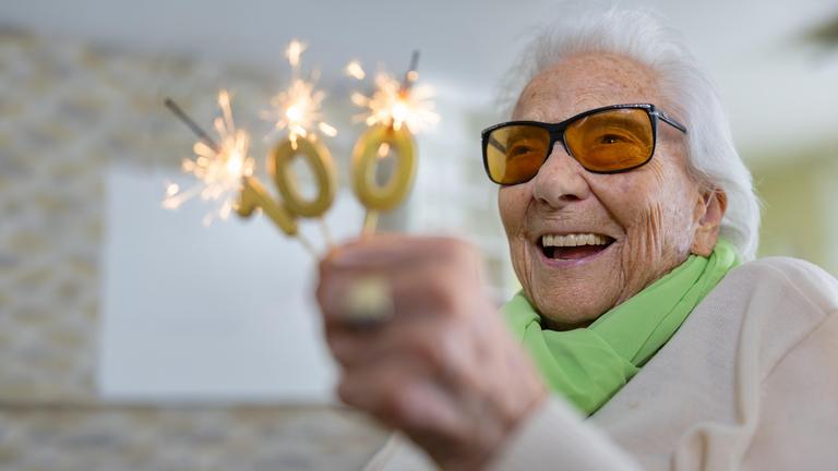 Friedel Zimmermann hält brennende Wunderkerzen in Form einer 100 in der Hand.