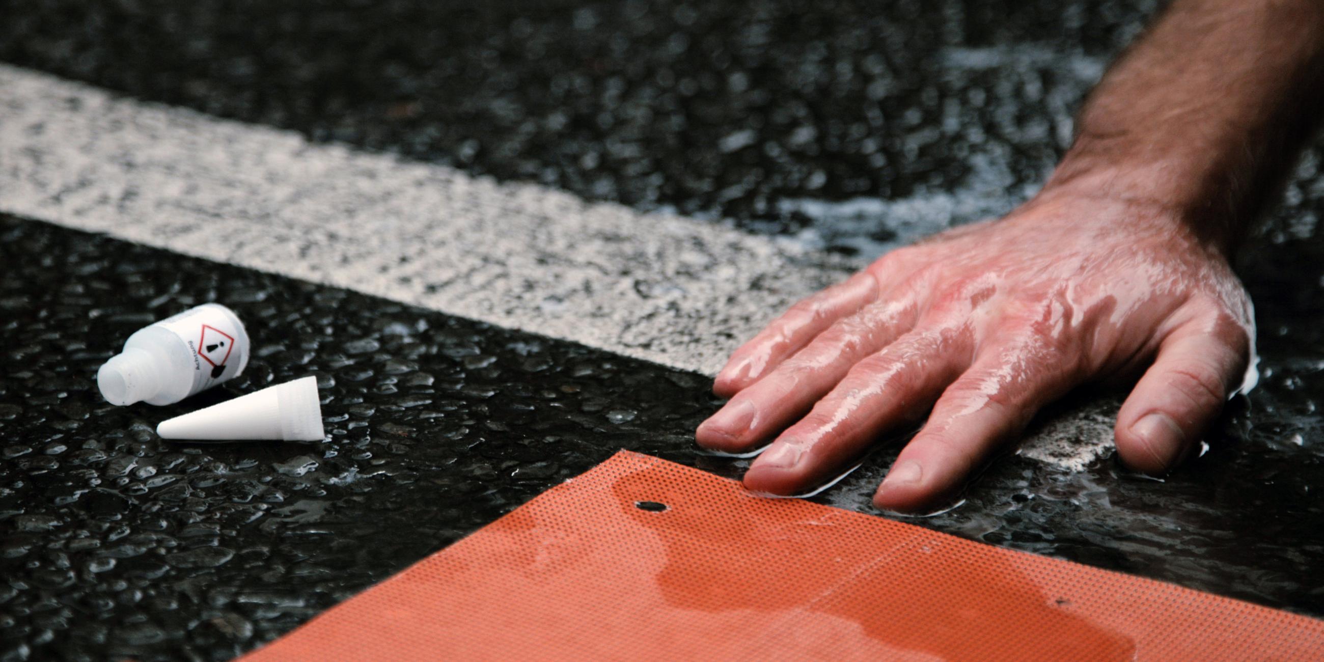 Die Hand eines Aktivisten der Letzten Generation ist auf der Straße festgeklebt.
