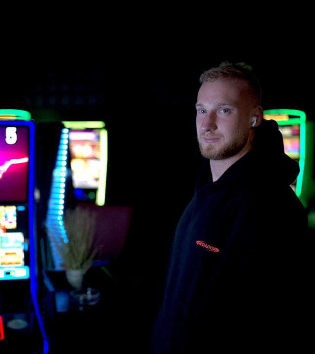 Tom steht neben Spielautomaten und schaut in die Kamera