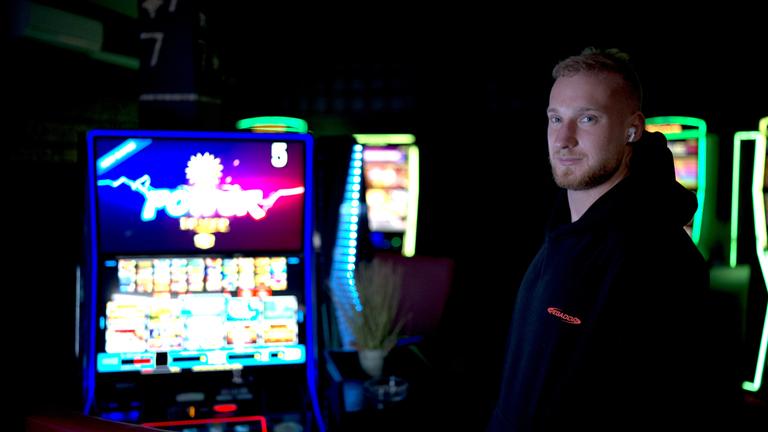 Tom steht neben Spielautomaten und schaut in die Kamera
