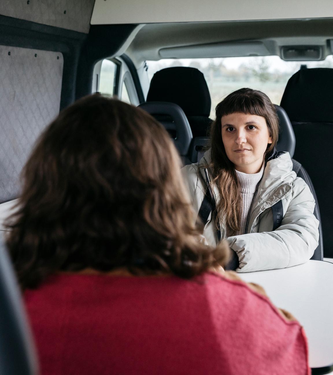 Sozialarbeiterin Miriam Peters von der Beratungsstelle "Land-Grazien" sitzt einer Frau in einem Transporter gegenüber, die nur von hinten zu sehen ist.