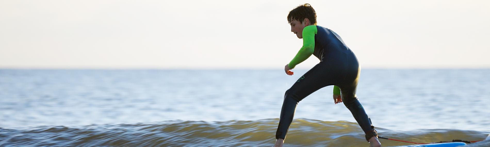 Junger Surfer auf dem Brett im Wasser.