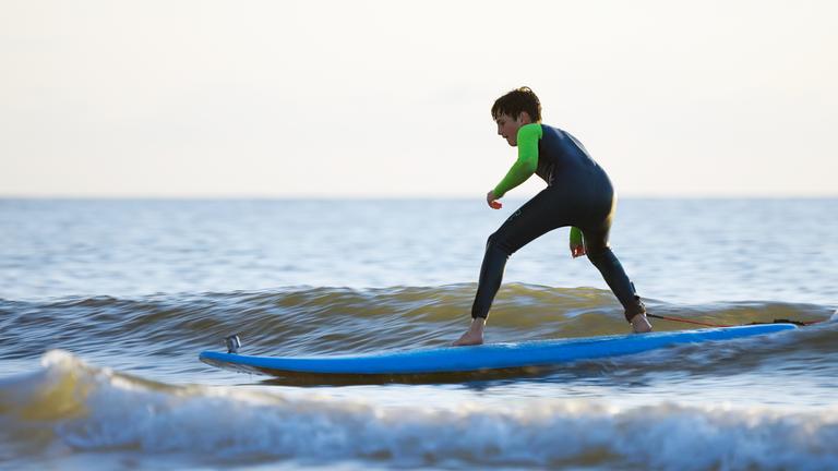 Junger Surfer auf dem Brett im Wasser.