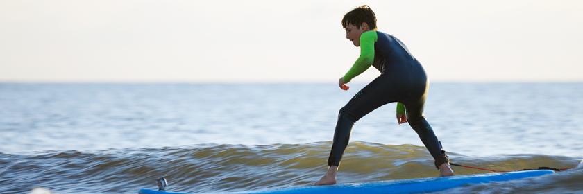 Junger Surfer auf dem Brett im Wasser.