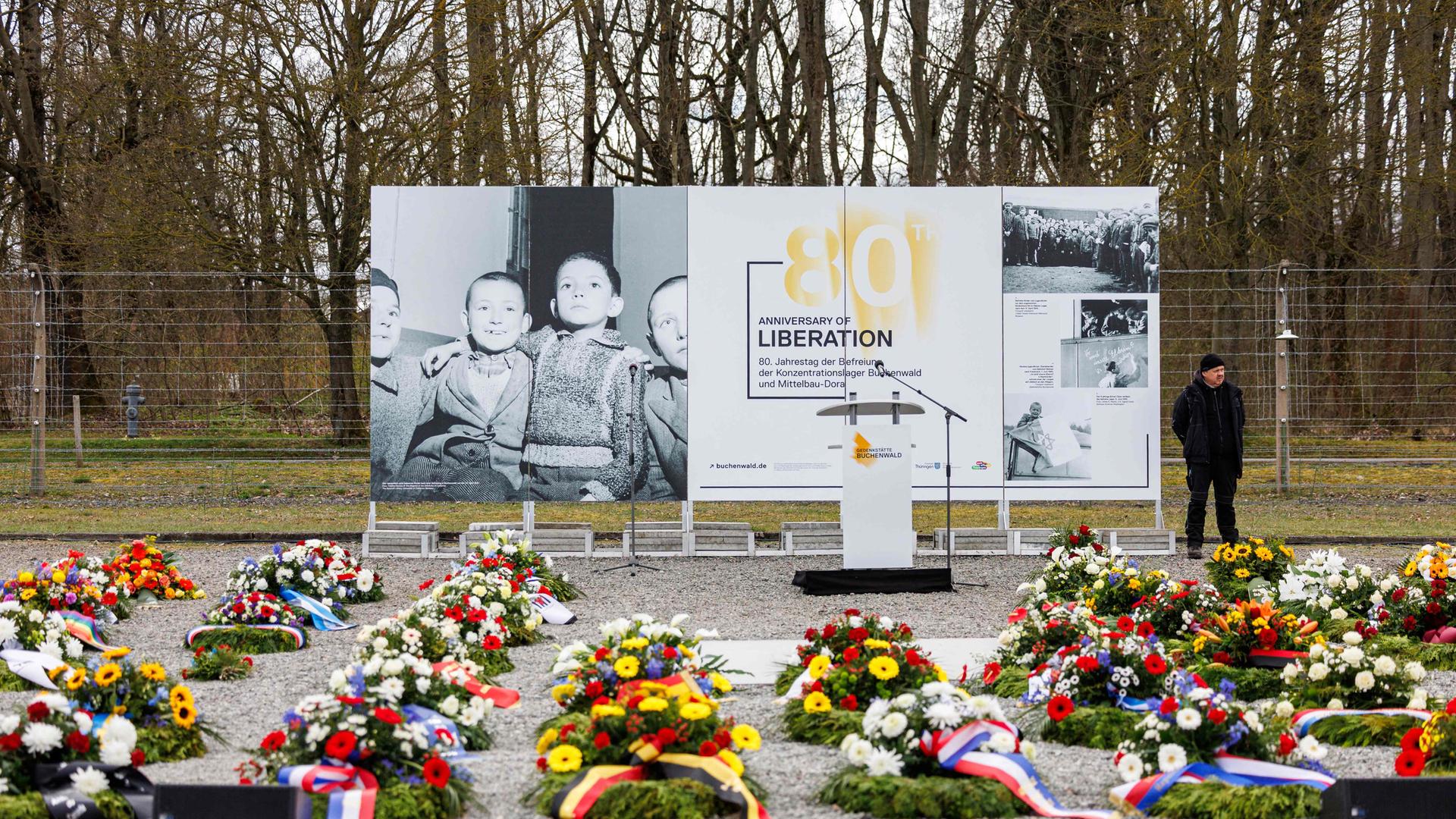 Blumenkränze liegen vor einem Plakat zum 80. Jahrestag der Befreiung des NS-Konzentrationslagers Buchenwald vor einer Gedenkfeier in Buchenwald bei Weimar.