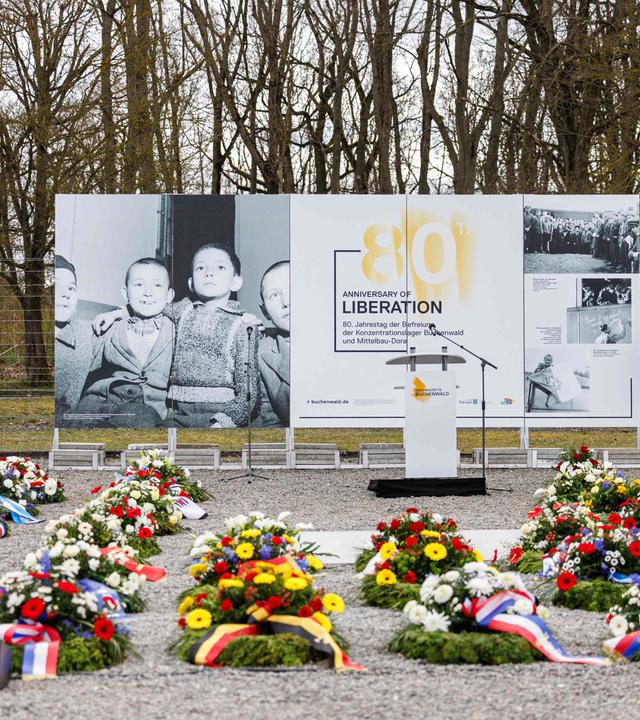 Blumenkränze liegen vor einem Plakat zum 80. Jahrestag der Befreiung des NS-Konzentrationslagers Buchenwald vor einer Gedenkfeier in Buchenwald bei Weimar.