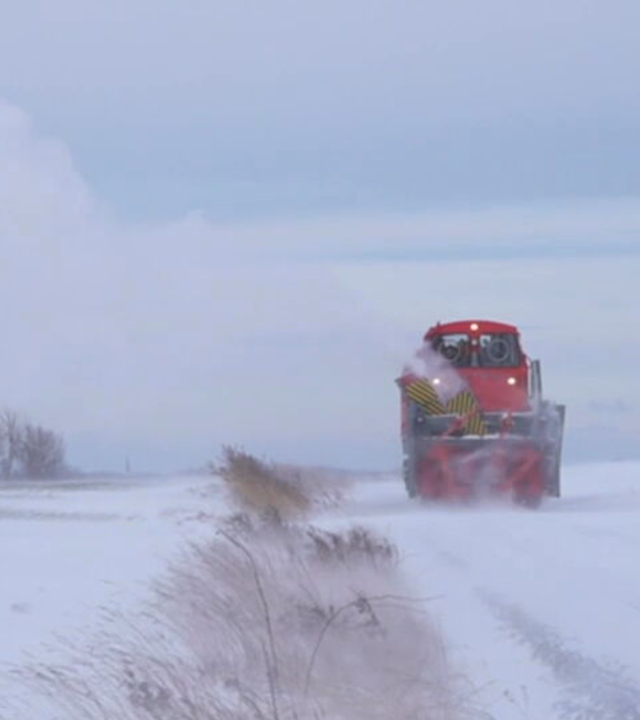 Die rote 80 Tonnen schwere Schneeschleuder fräst sich ihren Weg durch die verschneite Bahnstrecke.
