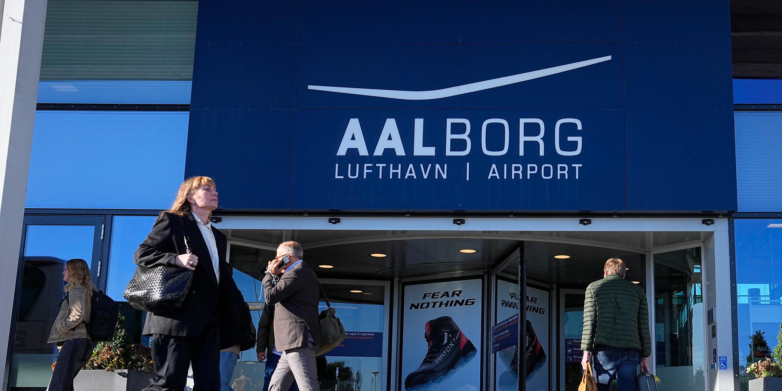 Menschen gehen am Eingang des Flughafens Aalborg vorbei, der nach einer nächtlichen Drohnensichtung vorübergehend geschlossen wurde.