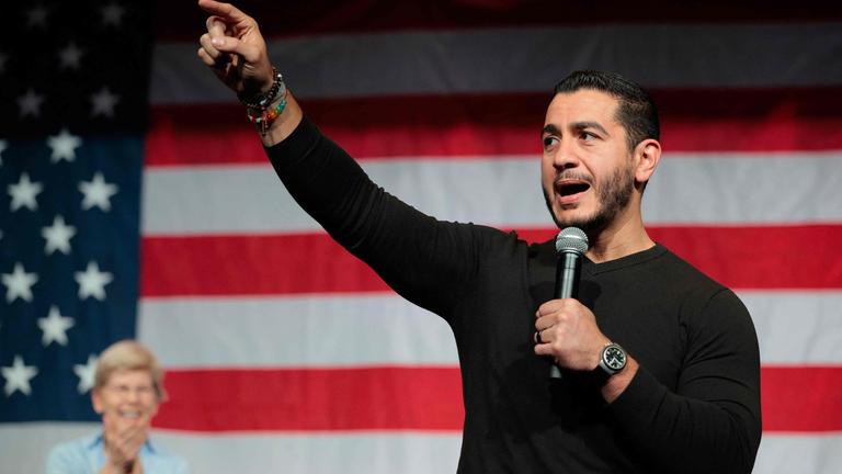 Der demokratische Kandidat Abdul El-Sayed bei einem Auftritt in Michigan vor einer großen USA-Flagge. Er gestikuliert ins Publikum.