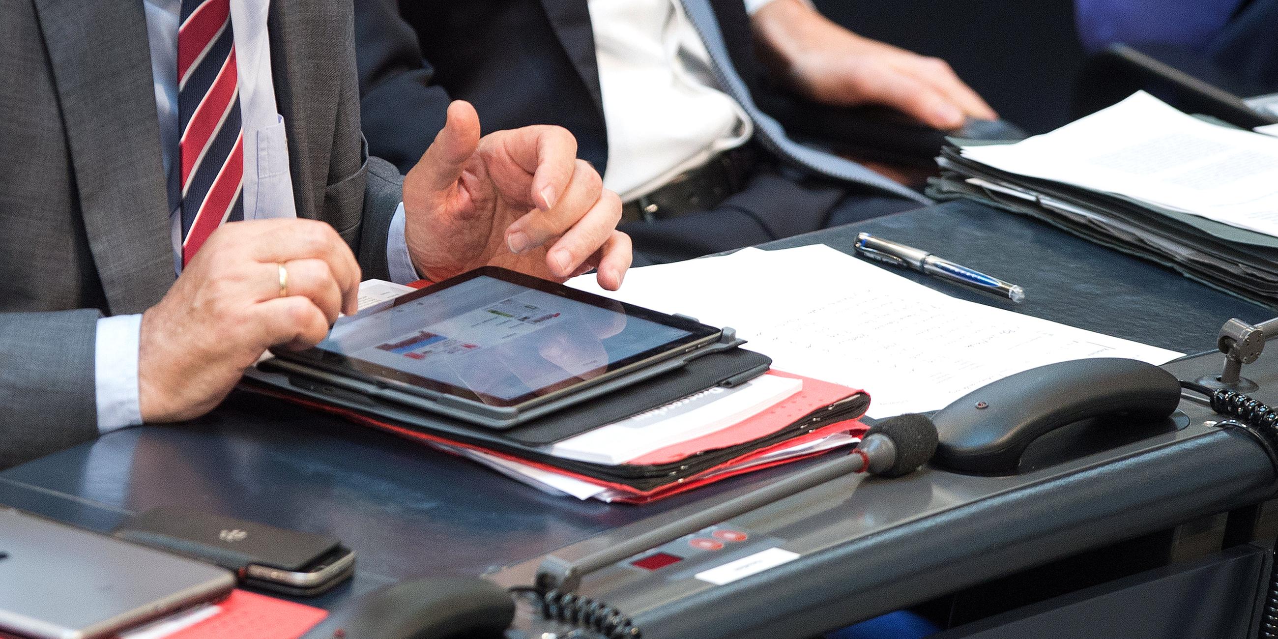 Abgeordneter mit Tablet und Akten im Bundestag