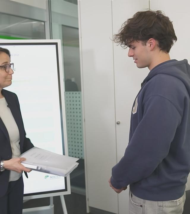 Schülerinnen und Schüler schreiben in einem großen Raum ihre Abiprüfung 
