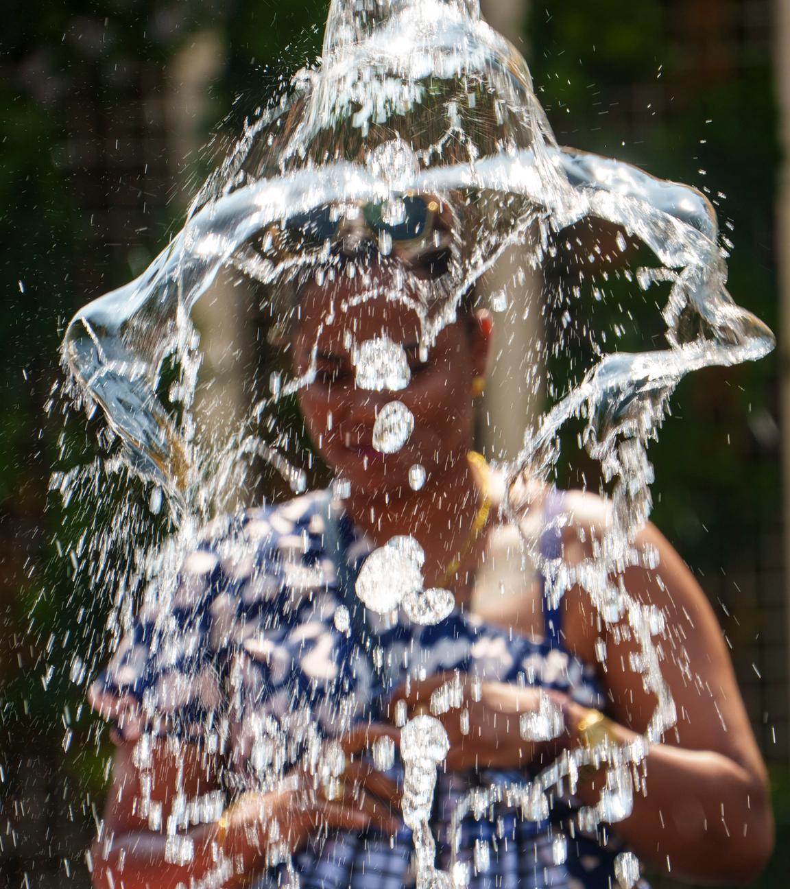 Eine Frau steht vor einer Wasserfontäne in einer Stadt